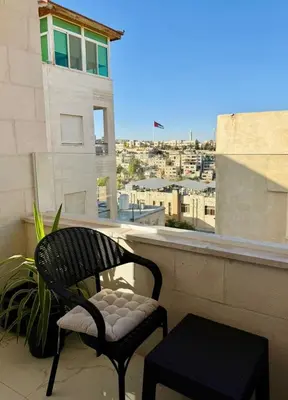 a chair sitting on a balcony with a view of a city at Beit Ahlan Suites 7 in Amman