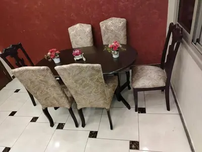 a black dining room table with four chairs and flowers at 10 seasoun House in Dawqarah