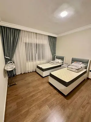 two beds in a large room with wooden floors at Modern Residence for families only in Amman