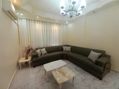a living room with a green couch and a table at Amman Central Elegant Apartment in Amman