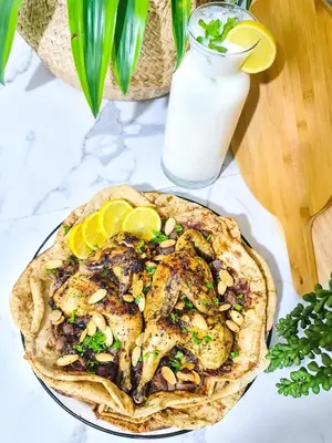 a table topped with a plate of chicken with lemon slices at العنبق هاوس
