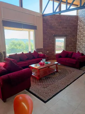 a living room with red couches and a coffee table at Chalet Adam- Ajloun شاليه ادم in Ajloun