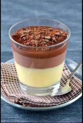 a cup of dessert on a plate with a spoon at kazami House in At-Tafilah