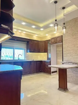 a large kitchen with wooden cabinets and a counter top at kazami House in At-Tafilah