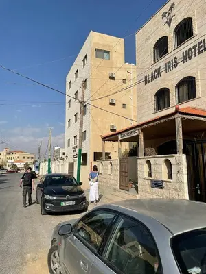 a couple of cars parked in front of a building at Black Iris Hotel in Madaba