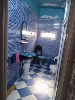 a blue tiled bathroom with a sink and a toilet at Zomik house in Al Qiḩāţī