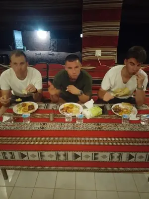 three men sitting at a table with plates of food at saleem with jeep tour in Wadi Rum