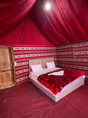 a bedroom with a bed in a red tent at saleem with jeep tour in Wadi Rum