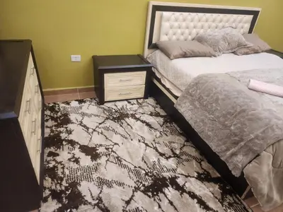 a bedroom with two beds and a dresser with a night stand at A big Family nice sunset flat in Amman