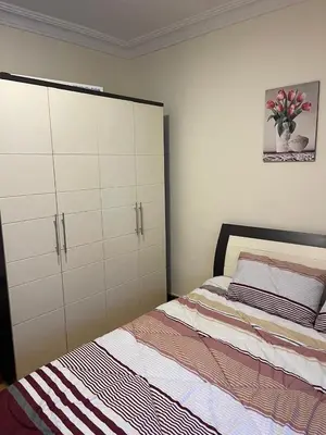 a bedroom with a bed and a large white cabinet at Furnished one bedroom apartment in Amman