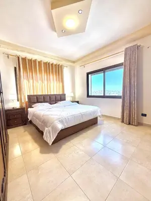a bedroom with a bed and a large window at Luxury 2 Bedroom Apartment in Amman