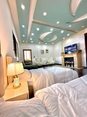 a room with three beds and a table with a lamp at Luxury 2 Bedroom Apartment in Amman
