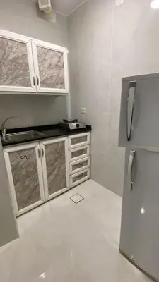 a kitchen with white cabinets and a refrigerator at aljumirah furnished appartments الجميرا للشقق المفروشة in Az Zarqa