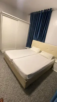 a large bed in a room with blue curtains at aljumirah furnished appartments الجميرا للشقق المفروشة in Az Zarqa