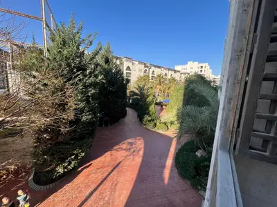 a view of a walkway with trees and a building at Al-Amaari Gardens Compound 3092 in Irbid