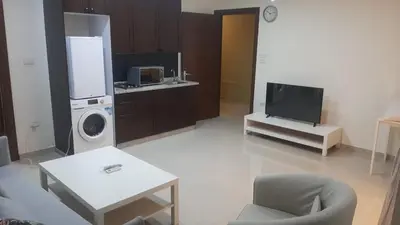 a living room with a tv and a washing machine at Al-Amaari Gardens Compound 3092 in Irbid
