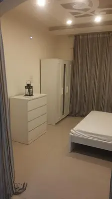 a white bedroom with a bed and a dresser at Al-Amaari Gardens Compound 3092 in Irbid