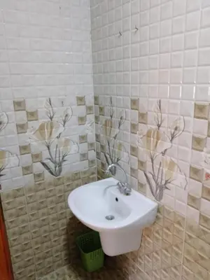 a bathroom with a white sink and tiled walls at Tea apartment in Aqaba