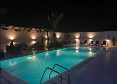 a large swimming pool at night with lights at Sunshine Chalet in Shūnat Nimrīn