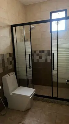 a bathroom with a toilet and a glass shower at شاليهات إيليت بانوراما فيو in Jerash