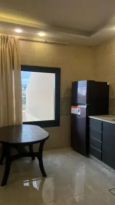 a kitchen with a table and a black refrigerator at شاليهات إيليت بانوراما فيو in Jerash