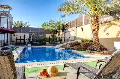 a swimming pool with chairs and a palm tree at Bahama-Oriya chalets in Al Rama