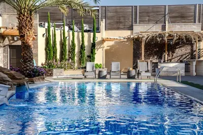 a large swimming pool with palm trees and chairs at Bahama-Oriya chalets in Al Rama