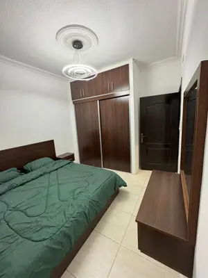 a bedroom with a green bed and a wooden cabinet at stay by university of Jordan in Amman