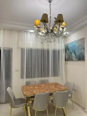 a dining room table with chairs and a chandelier at stay by university of Jordan in Amman