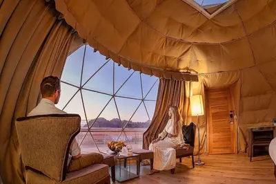 a man and woman sitting in a room with a large window at Celestial Mirage Camp in Wadi Rum
