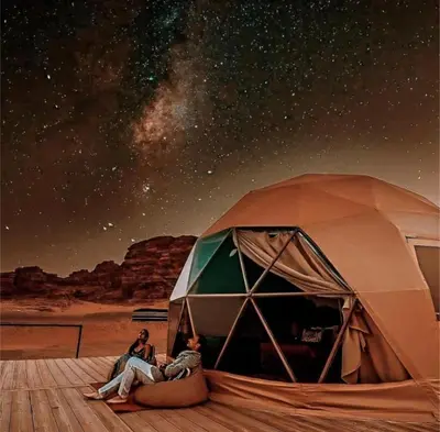 a couple of people sitting in front of a tent at Celestial Mirage Camp in Wadi Rum
