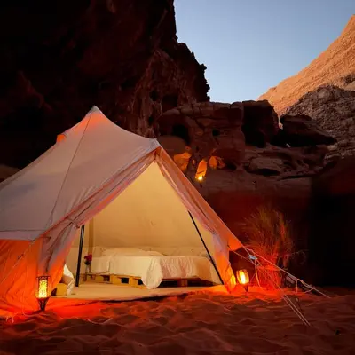 a tent with a bed in the desert at night at The Legacy of Wadi Rum in Wadi Rum