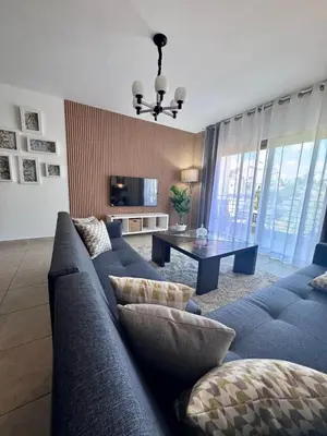 a living room with a blue couch and a table at Glow and Grace in Abdoun Best location in Amman