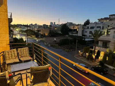 two chairs sitting on a balcony with a view of a city at Loom & Light In the best location in Abdoun Amman in Amman