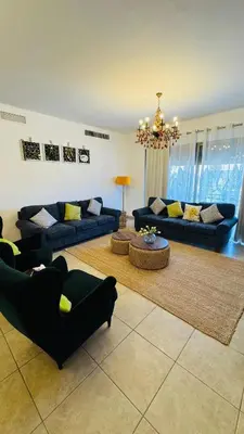 a living room with blue couches and a chandelier at Loom & Light In the best location in Abdoun Amman in Amman