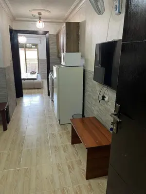 a kitchen with a refrigerator and a table and a tv at Central modern affordable studio in Amman