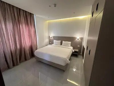 a bedroom with a white bed and a window at Masaken Hotel Apartment in Amman