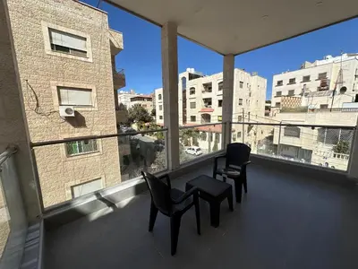 a balcony with two chairs and a table and a building at Masaken Hotel Apartment in Amman