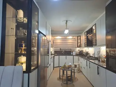 a kitchen with white cabinets and a table in it at شقة مميزة in Rujm Maghghijhah