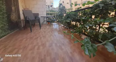 a balcony with a wooden floor and chairs and plants at شقة مميزة in Rujm Maghghijhah
