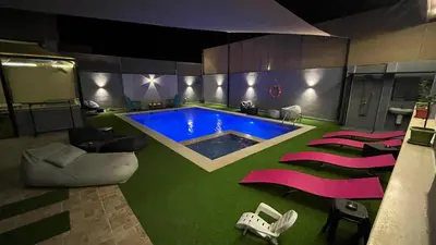 a living room with a swimming pool and some chairs at T Cozy Chalet in Ash Shāghūr