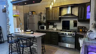 a kitchen with a refrigerator and a counter with stools at Cozy and well-located 2 bedroom flat near a mall in Amman