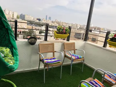 a balcony with two chairs and a view of a city at Cozy and well-located 2 bedroom flat near a mall in Amman