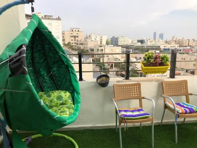 a balcony with two chairs and a hammock on a roof at Cozy and well-located 2 bedroom flat near a mall in Amman
