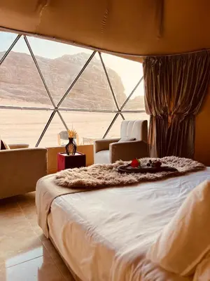 a large bed in a room with a large window at DESERT BREATHS lUXURY CAMP in Wadi Rum