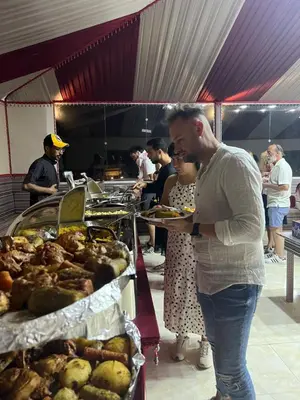 a man holding a plate of food at a buffet at DESERT BREATHS lUXURY CAMP in Wadi Rum