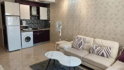 a living room with a couch and a kitchen at Nice cozy place in Amman