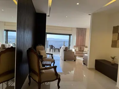 two pictures of a living room with chairs and a couch at The view in Māḩiş