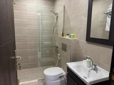 a bathroom with a shower and a toilet and a sink at The view in Māḩiş