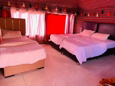 two beds in a room with red and white at Crescent Camp & Tours in Wadi Rum